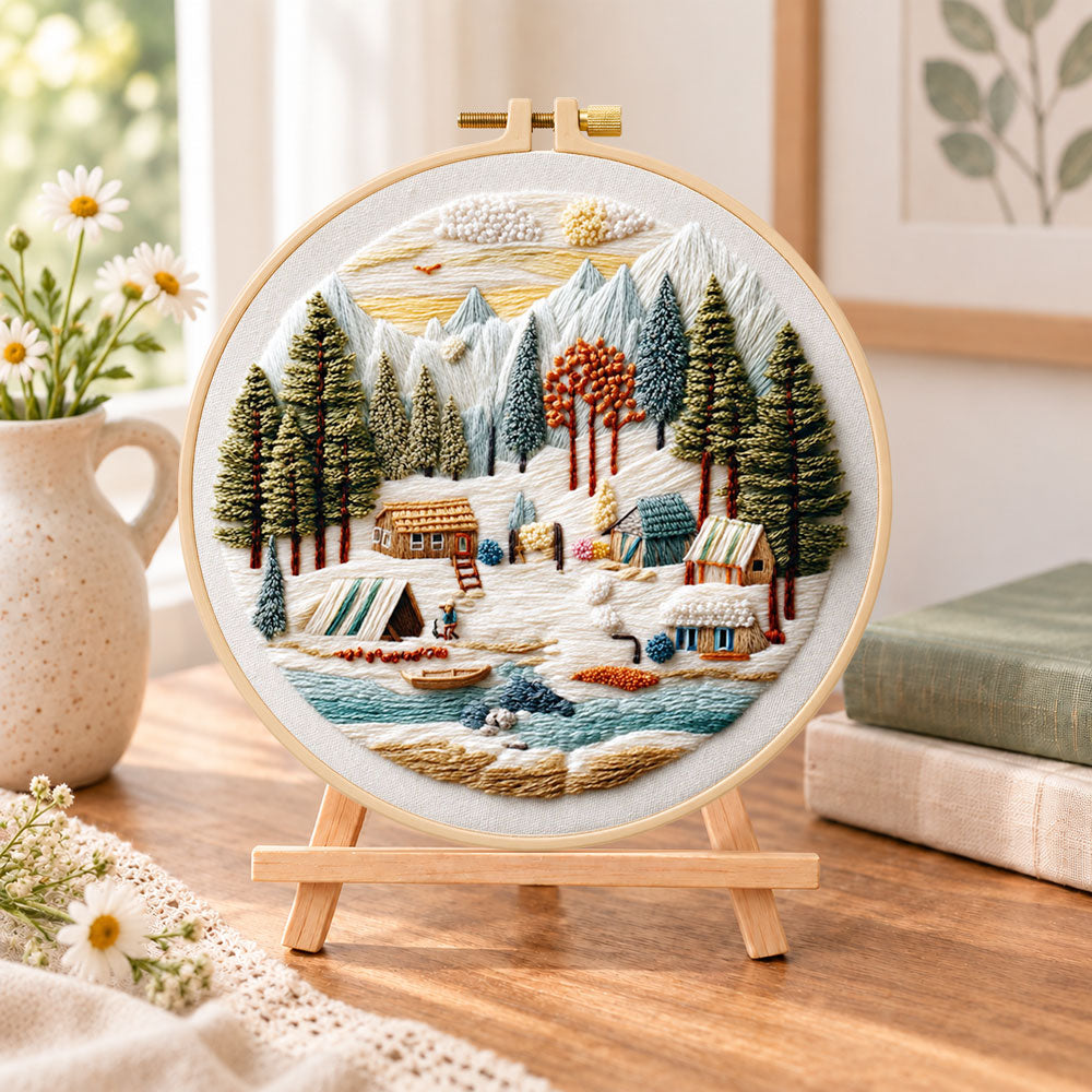 Mountain winter camp embroidery kit finished hoop displayed on a wooden stand as cozy tabletop decor