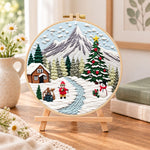 Mountain winter wonderland embroidery kit finished hoop displayed on a wooden stand as cozy tabletop decor