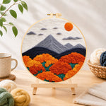 Finished mountains and lush orange roses needle felting displayed on a wooden easel