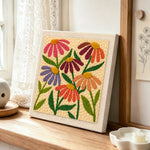 Multicolor daisies punch needle artwork displayed on a table