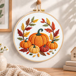 Multiple pumpkins with autumn leaves embroidery hoop wall art displayed as warm and cozy handmade home decor