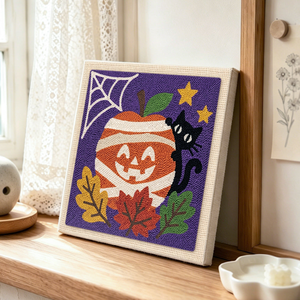 Mummy apple and black cat punch needle artwork displayed on a table