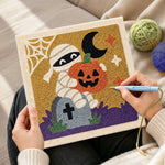 Creating handmade mummy holding pumpkin punch needle artwork