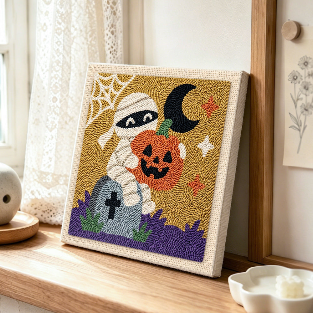 Mummy holding pumpkin punch needle artwork displayed on a table