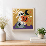 Finished mummy holding pumpkin artwork displayed on a wall
