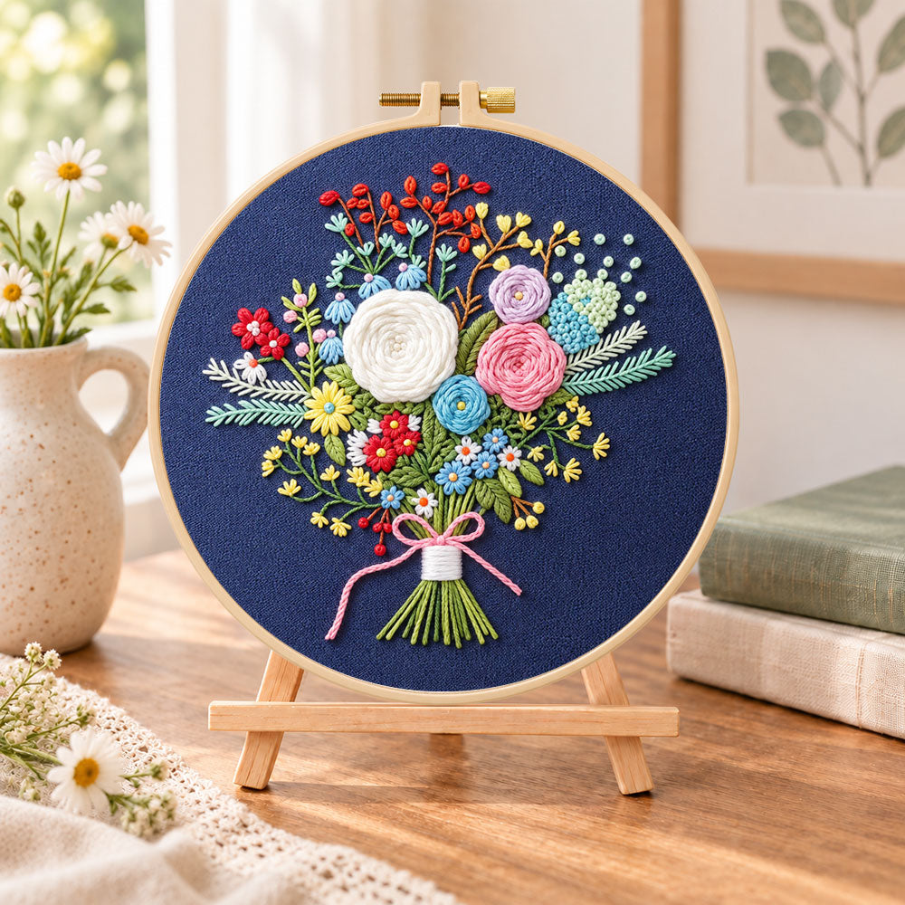 Navy floral bouquet embroidery kit finished hoop displayed on a wooden stand as cozy tabletop decor