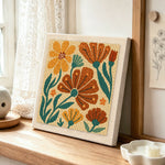 Orange and brown florals punch needle artwork displayed on a table