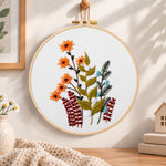 Orange daisy floral sprig embroidery hoop wall art displayed as warm and cozy handmade home decor