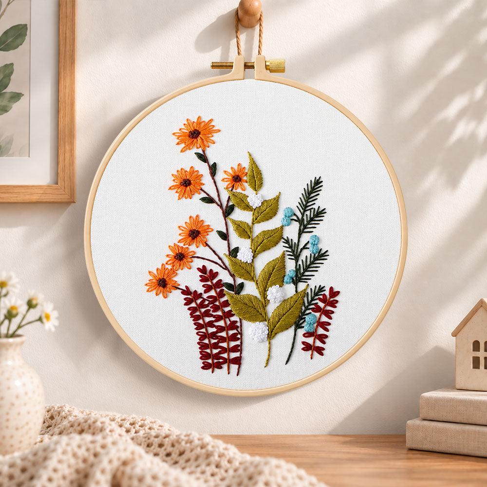 Orange daisy floral sprig embroidery hoop wall art displayed as warm and cozy handmade home decor