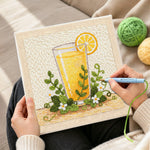 Creating handmade orange juice and green leaves punch needle artwork