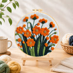 Finished orange-red flower cluster needle felting displayed on a wooden easel