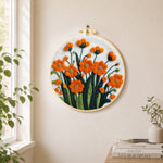 Orange-red flower cluster needle felt wall art displayed in a bright home interior