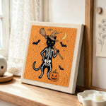 Orange skeleton witch cat punch needle artwork displayed on a table