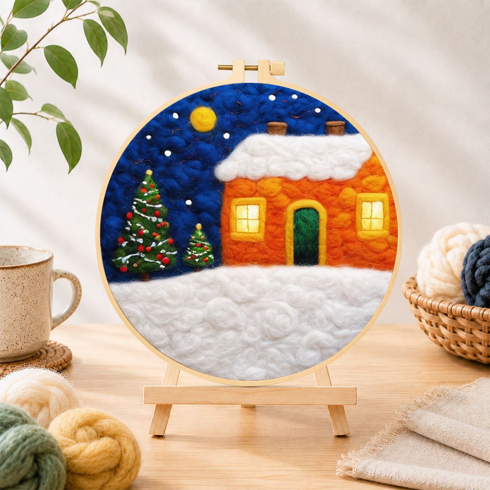 Finished orange snowy house and christmas trees needle felting displayed on a wooden easel