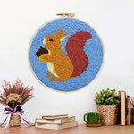 Finished orange squirrel holding pine cone artwork displayed on a wall