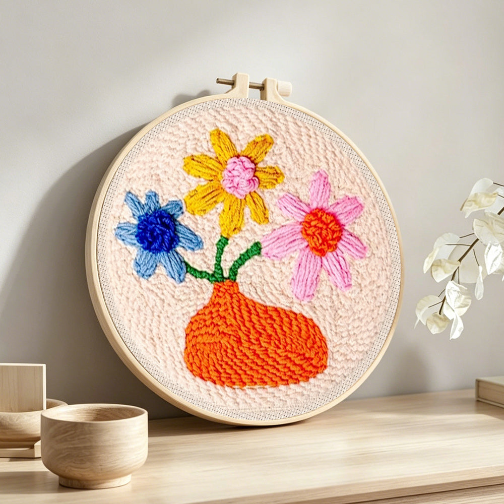 Orange vase with colorful flowers punch needle artwork displayed on a table