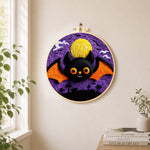 Orange-winged bat under the purple night needle felt wall art displayed in a bright home interior