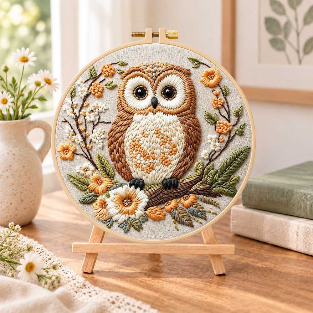 Owl on blossom branch embroidery kit finished hoop displayed on a wooden stand as cozy tabletop decor