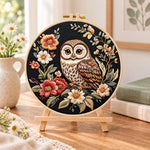 Owl on dark floral embroidery kit finished hoop displayed on a wooden stand as cozy tabletop decor