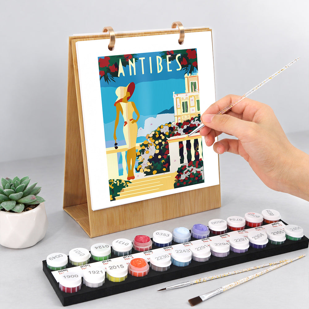 Hand painting a colorful Antibes seaside illustration on the Scenic Getaways Paint by Numbers Desk Calendar