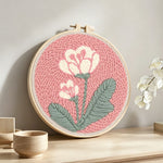Pale pink background with white flowers punch needle artwork displayed on a table