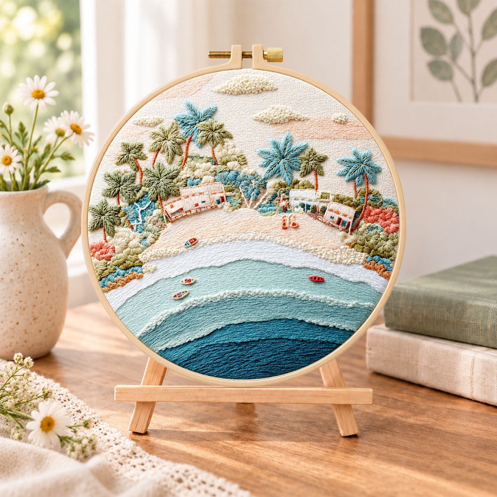 Pastel beach coast embroidery kit finished hoop displayed on a wooden stand as cozy tabletop decor
