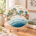 Pastel beach coast embroidery kit finished hoop displayed on a wooden stand as cozy tabletop decor