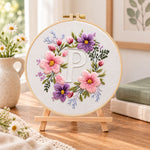 Pastel blossoms and letter p embroidery kit finished hoop displayed on a wooden stand as cozy tabletop decor