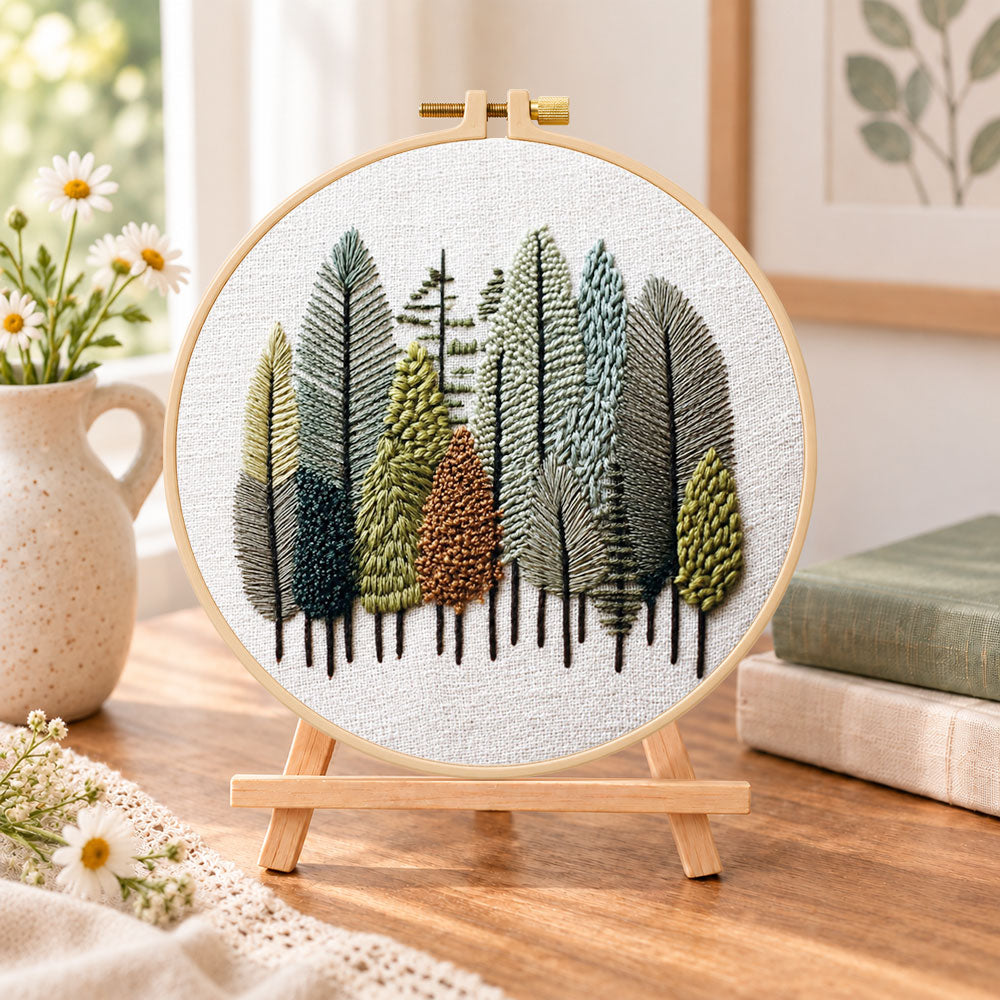 Pastel forest grove embroidery kit finished hoop displayed on a wooden stand as cozy tabletop decor