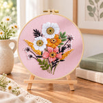 Pastel pink florals embroidery kit finished hoop displayed on a wooden stand as cozy tabletop decor