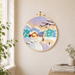 Pastel twilight snowy cabin needle felt wall art displayed in a bright home interior