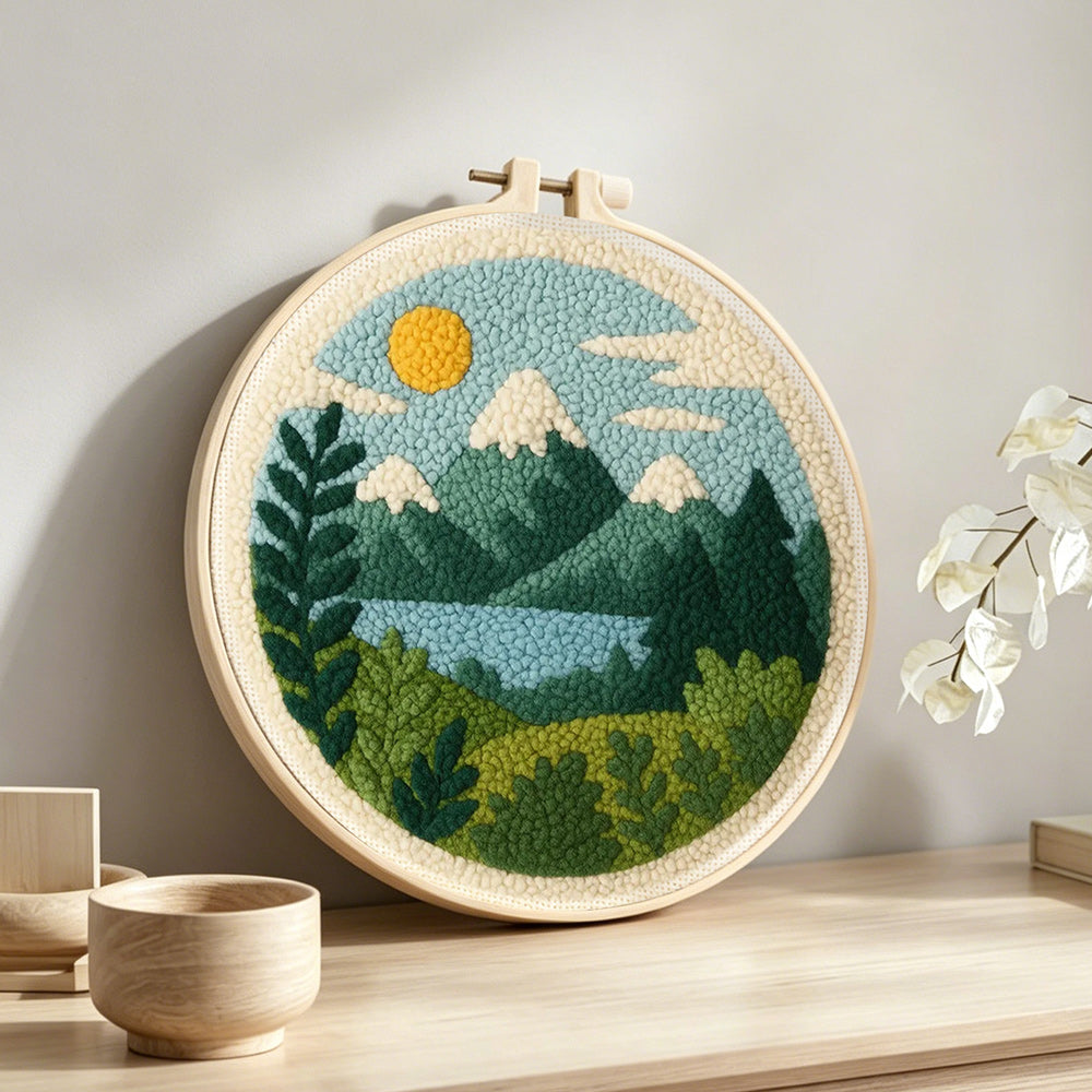 Peaceful mountain and lake punch needle artwork displayed on a table
