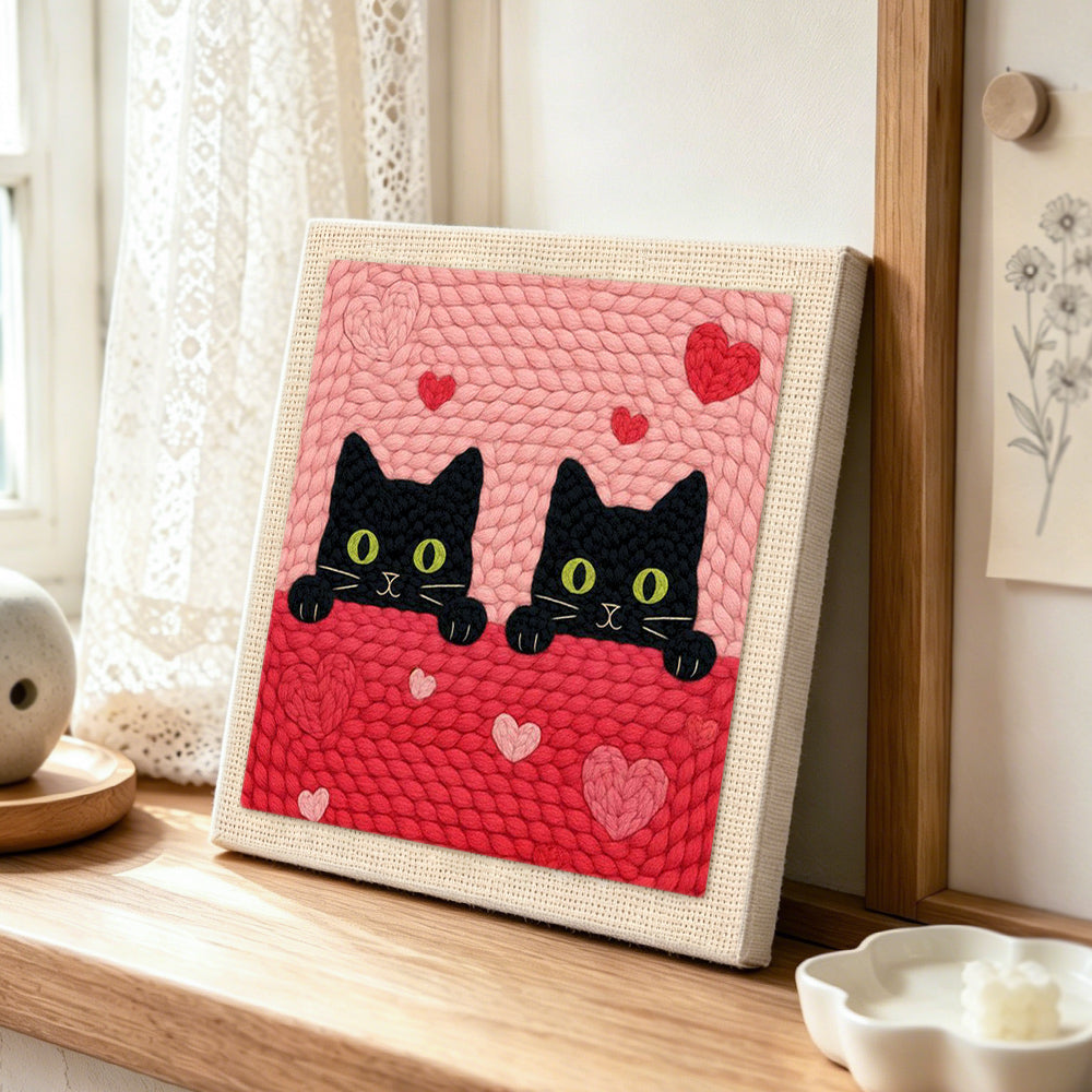 Peeking black cat duo with green eyes punch needle artwork displayed on a table