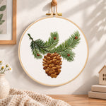 Pine branch and cone embroidery hoop wall art displayed as warm and cozy handmade home decor