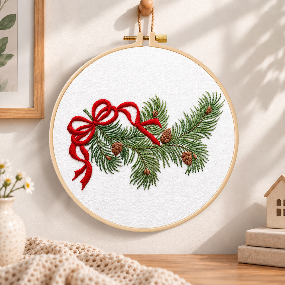 Pine branch with bow embroidery hoop wall art displayed as warm and cozy handmade home decor