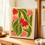 Pink and red bell flowers punch needle artwork displayed on a table