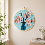 Pink blossom in blue vase needle felt wall art displayed in a bright home interior