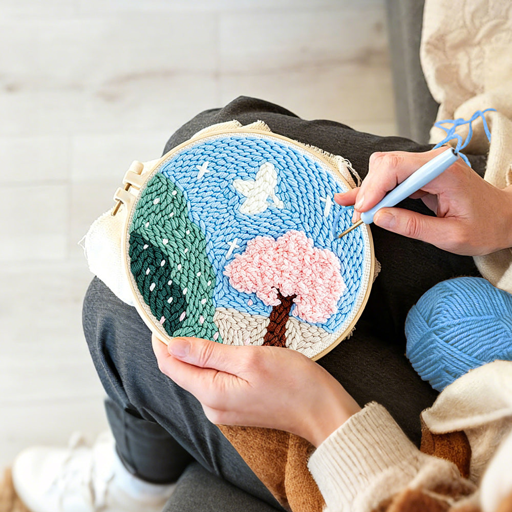 Creating handmade pink blossom tree and green mountains punch needle artwork