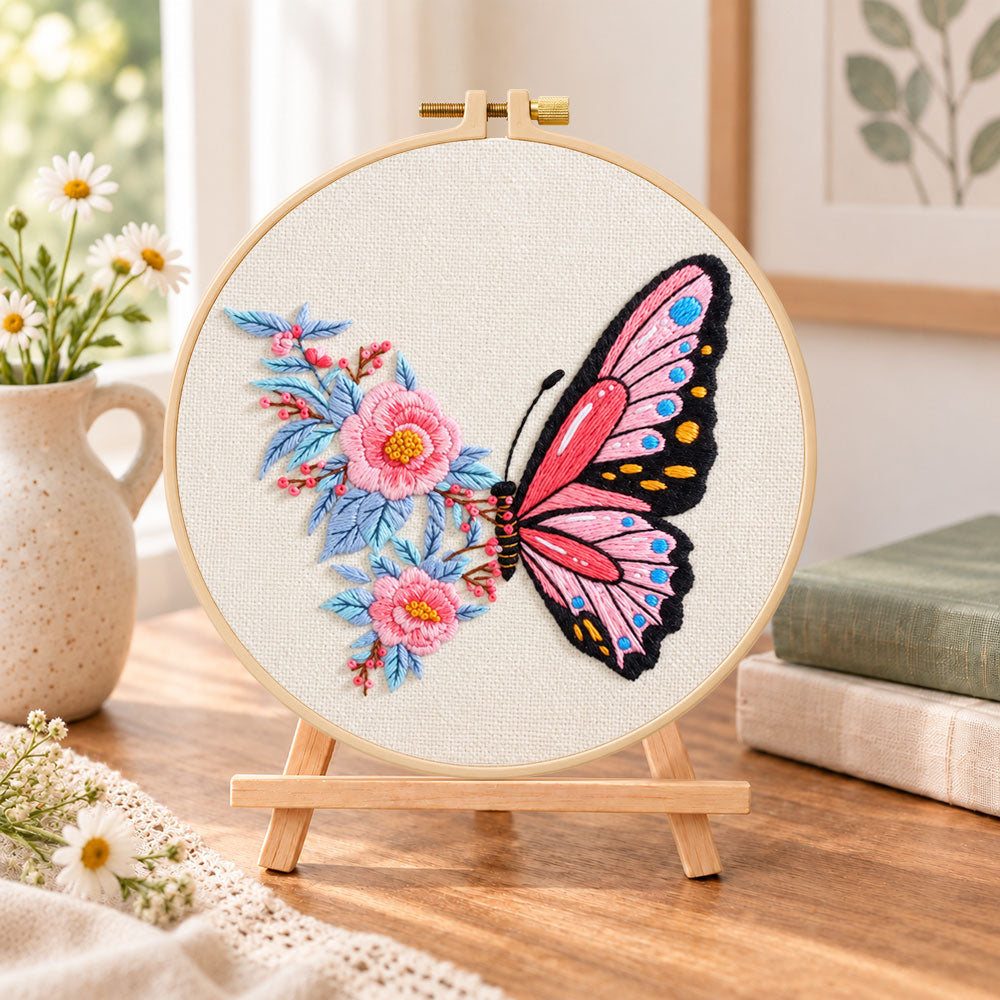 Pink butterfly with peony embroidery kit finished hoop displayed on a wooden stand as cozy tabletop decor