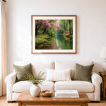 Finished pink cherry blossoms over a peaceful river cross stitch artwork displayed as home decor