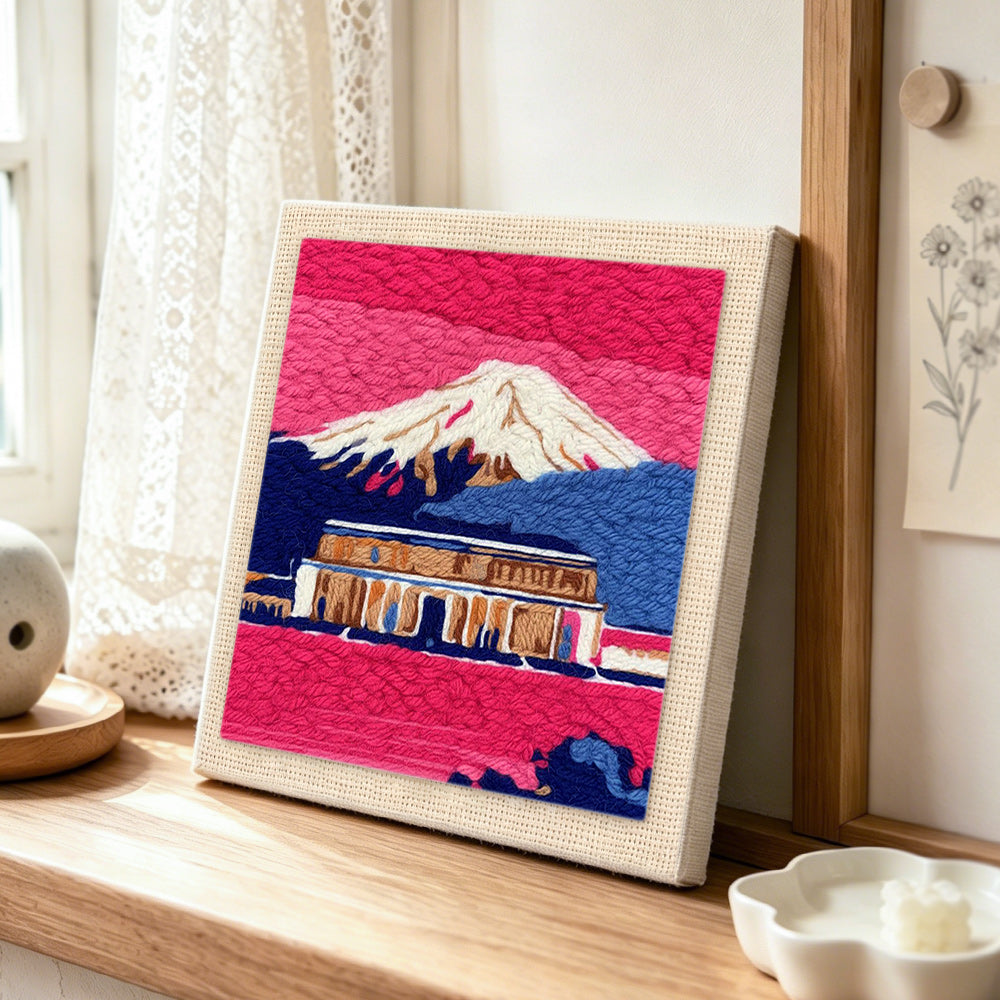 Pink dusk temple and snowy mountain punch needle artwork displayed on a table
