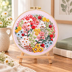 Pink floral art with ladybugs embroidery kit finished hoop displayed on a wooden stand as cozy tabletop decor