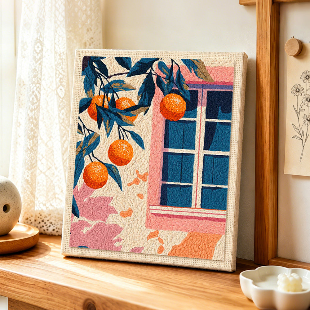 Pink window and orange tree punch needle artwork displayed on a table