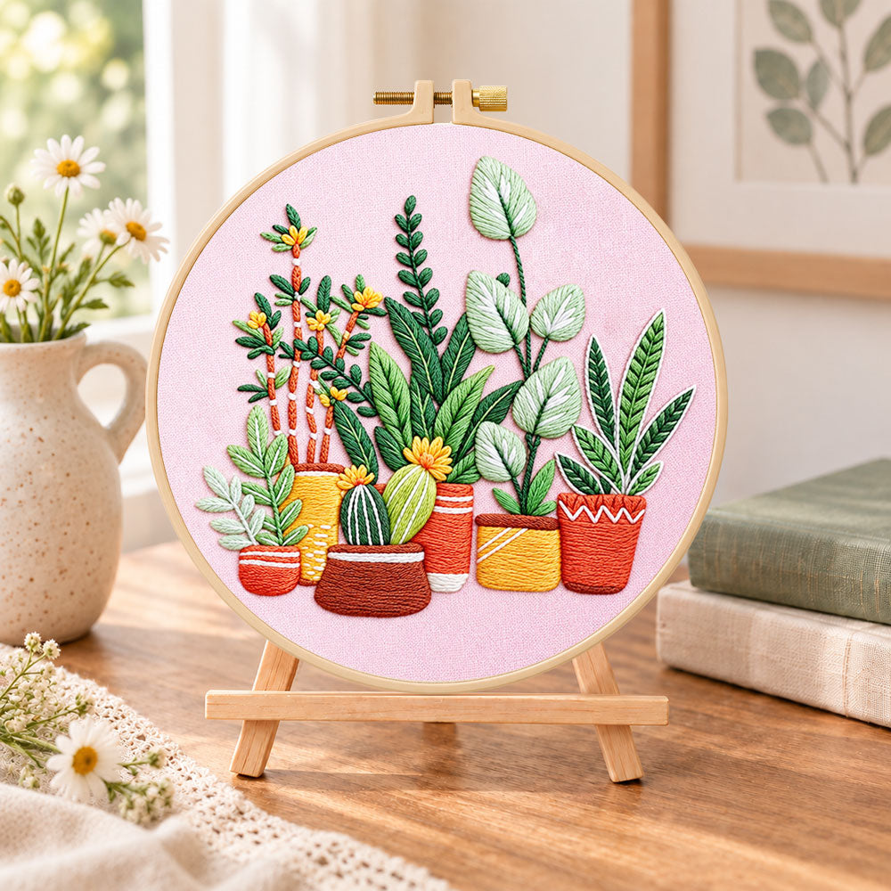 Potted plants on pink fabric embroidery kit finished hoop displayed on a wooden stand as cozy tabletop decor