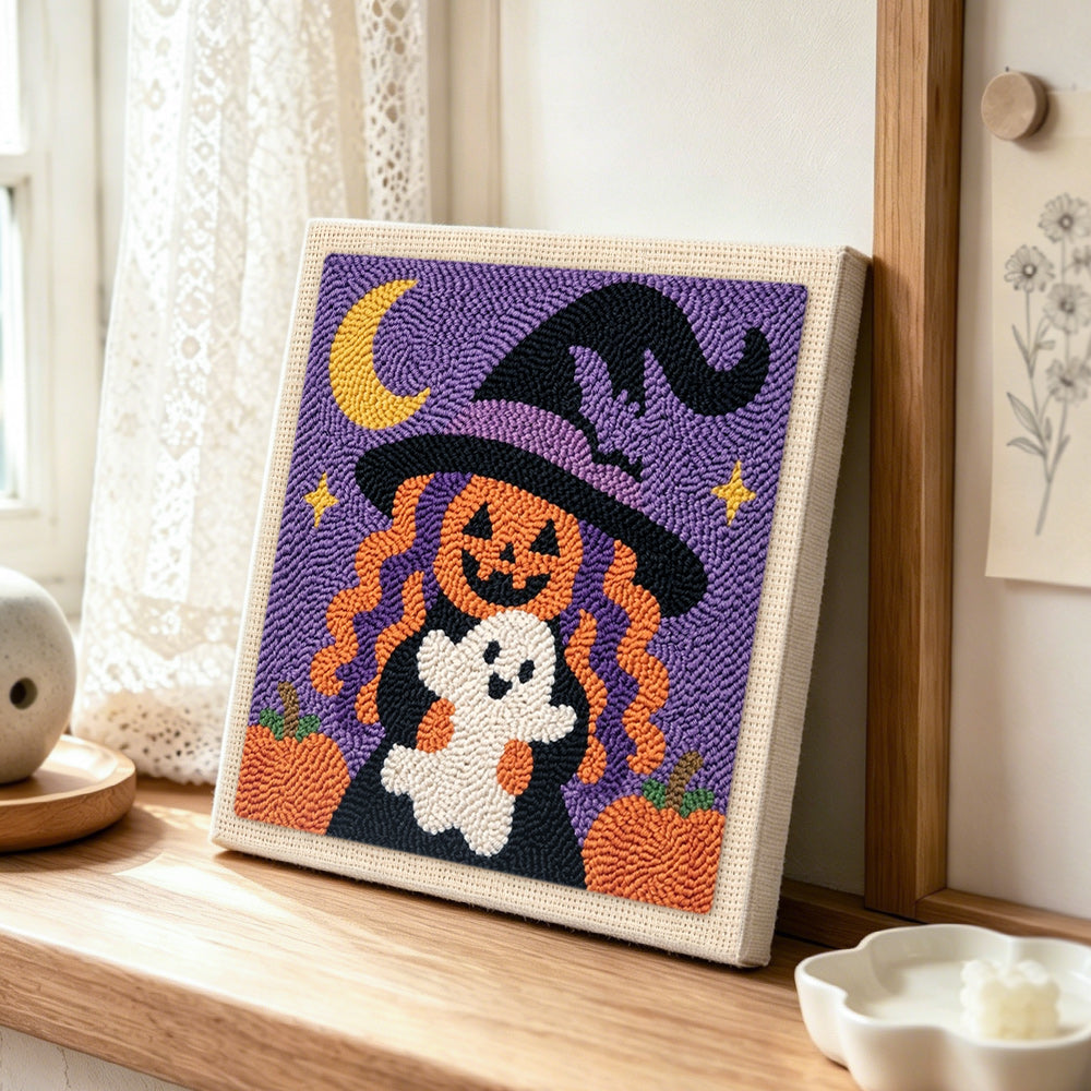Pumpkin witch holding little ghost punch needle artwork displayed on a table