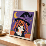Pumpkin witch holding little ghost punch needle artwork displayed on a table