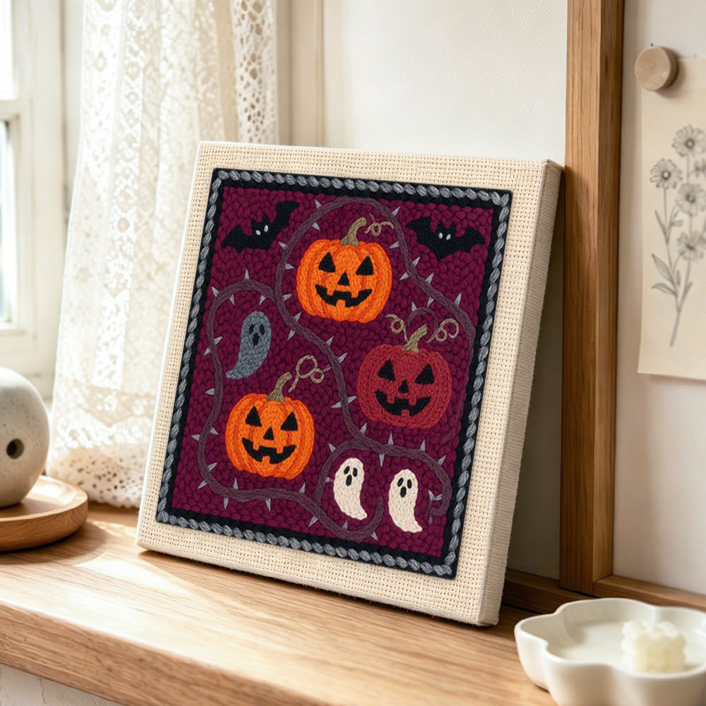 Pumpkins and little ghosts punch needle artwork displayed on a table