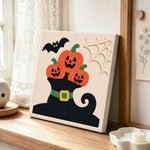 Pumpkins on witch hat punch needle artwork displayed on a table