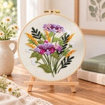 Purple and gold sprigs embroidery kit finished hoop displayed on a wooden stand as cozy tabletop decor