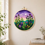 Purple dusk sky and tall wildflowers needle felt wall art displayed in a bright home interior
